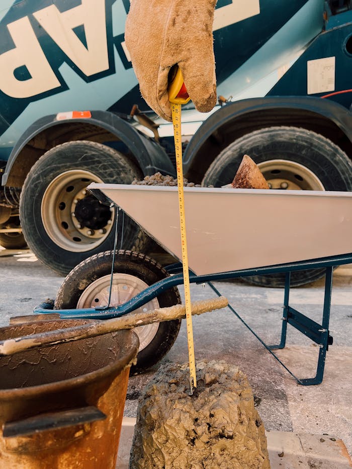 Worker measures cement mix consistency with tape measure at construction site.