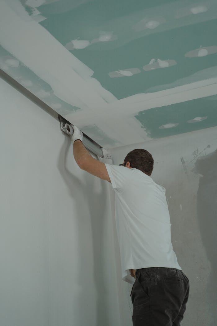 A man works meticulously on drywall installation during a house renovation.